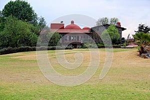 Colonnial farm and country house, stone and red brick construction with arches and green grass garden