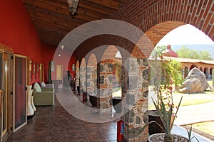 Colonnial farm and country house, stone and red brick construction with arches and green grass garden