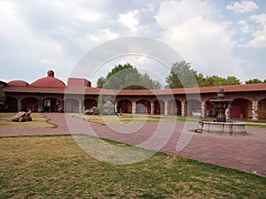 Colonnial farm and country house, stone and red brick construction with arches and green grass garden photo
