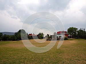 Colonnial farm and country house, stone and red brick construction with arches and green grass garden