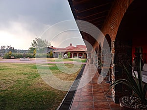 Colonnial farm and country house, stone and red brick construction with arches and green grass garden