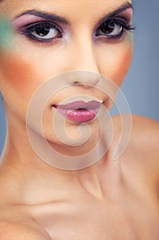 Color accentuates her already striking feautures. a beautiful young woman covered in makeup.