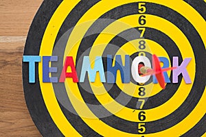 Color alphabets TEAMWORK acronym on dartsboard background with red arrow hit center of target. Business strategy and management