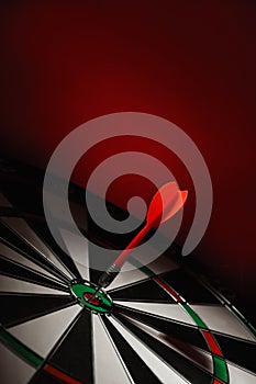 Color arrow hitting target on dart board against red
