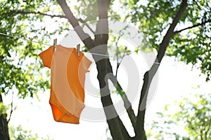 Color baby onesie hanging on clothes line outside