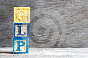 Color block in word GLP Abbreviation of Good laboratory practice on wood background