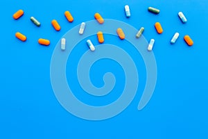 Color capsules. Medicine pills on blue background top view copy space pattern