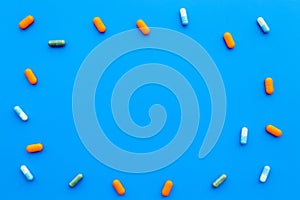 Color capsules. Medicine pills on blue background top view copy space pattern