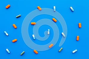 Color capsules. Medicine pills on blue background top view copy space pattern