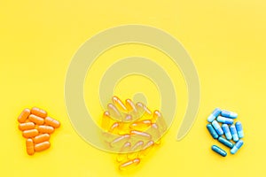 Color capsules. Medicine pills on yellow background top view copy space