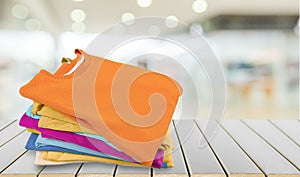 Stack of colorful t-shirts on wooden table