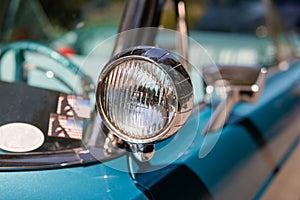 Color detail on the headlight of a vintage car sky blue color and shiny chrome, selective focus, turquoise