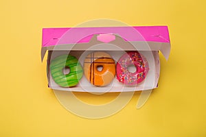 Color donuts in box on yellow background. Free space.