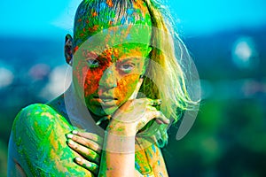 Color face with colorful holi splash. Cheerful young woman with colorful paint on bodies having fun at holi festival