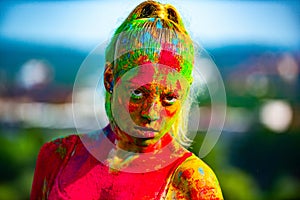 Color face with colorful holi splash. Close-up portrait of a young woman with colorful holi powder. Multi colored face