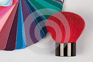 Color fan deck with samples of various paints with red brush for makeup