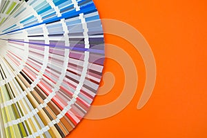 Color guide close up. Assortment of flowers for design. Color palette fan on orange background A graphic designer chooses colors