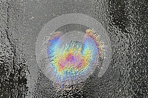 Color image of fuel oil spilled on asphalt. Rainbow colors of oil residue on water.