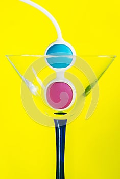 Color Kegel balls in a triangle cocktail glass. Concept of women health