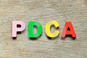 Color letter in word PDCA Abbreviation of plan do check act on wood background