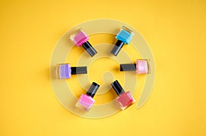 Color nail polish bottles on yellow background composition