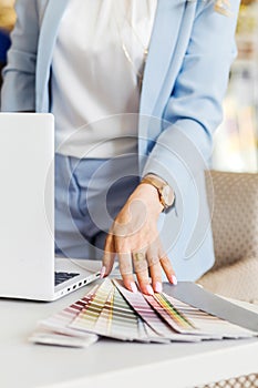 Color palette, laptop and female hands close up. Interior designer work concept