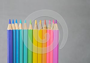 Color pancils with grey background, Group of colorful pencils laying in row striaght line made by pencil tips close up, copy