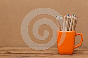 Color pencil in the cup on wooden background