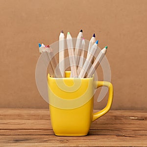 Color pencil in the cup on wooden background