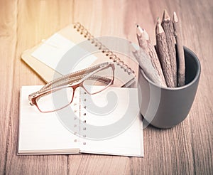 Color pencil made of branches with glasses and note book on wood photo