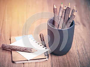 Color pencil made of branches with glasses and note book on wood photo