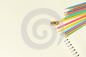 Color pencil and pencil sharpener on blank spiral notebook on white background. Place for your text