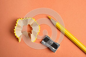 Color pencil, sharpener and shavings on orange background