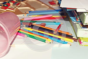 Color pencils and books are scattered on the children`s table.