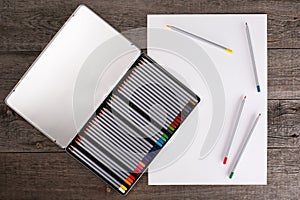 Color pencils in case and blank paper on wooden table