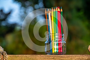 Color pencils in clear jar on wooden swing