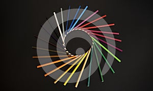 Color pencils isolated on the black background forming a circle.  Rays of color pencils