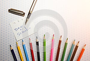 Color pencils lying on cute spotted background with dots. Back to school concept and sign written with a pen. Colorful art