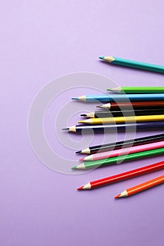 Color pencils lying on pastel purple background. Back to school concept. Colorful art studying and painting process. Drawing with