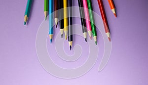 Color pencils lying on pastel purple background. Back to school concept. Colorful art studying and painting process. Drawing with