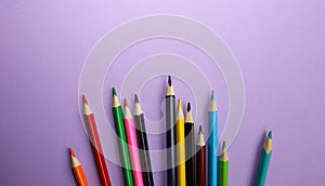 Color pencils lying on pastel purple background. Back to school concept. Colorful art studying and painting process. Drawing with