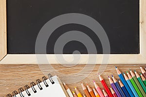 Color pencils with notebook and blackboard