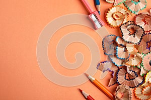 Color pencils, sharpener and shavings on orange, flat lay. Space for text