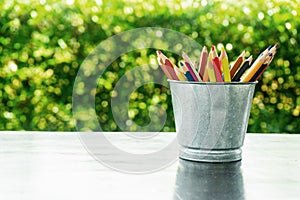 Color pencils in tin can, wood table