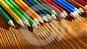 Color pencils in a writing-glass. Draw with colored pencils on white paper and a wooden table. Wooden retro table.