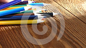 Color pencils in a writing-glass. Draw with colored pencils on white paper and a wooden table. Wooden retro table.