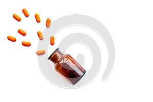 Color pills spilling out of a pill bottle on white background top view copy space