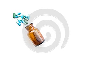 Color pills spilling out of a pill bottle on white background top view copy space