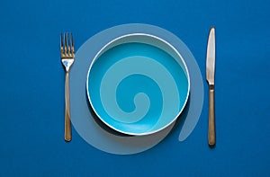 Color plate fork and knife isolated on blue background.