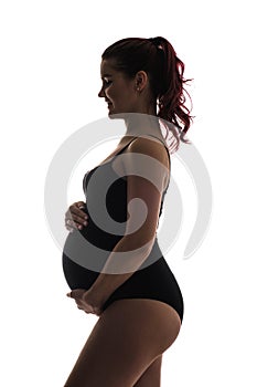 Color silhouette of a pregnant young girl. Holds a belly and smiles.